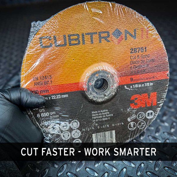 A gloved hand holding a 3M Cubitron II cut-off wheel from Obtainium Scientific Surplus, showing the front label with specifications and brand logo.